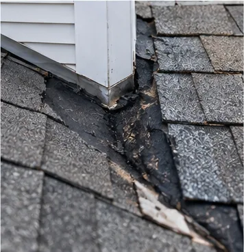 Damaged shingles where a roof meets a wall, a common leak point